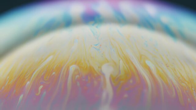 シャボン玉の表面で渦を巻くパステルの虹色