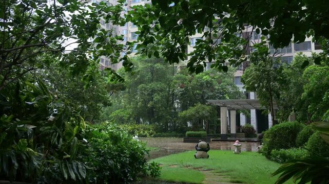 Heavy rain and strong wind sweep through a residential community garden during typhoon