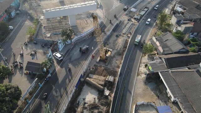 Aerial view of road construction site with a crane and vehicles on a busy street in Yogyakarta, Special Region of Yog, Indonesia.