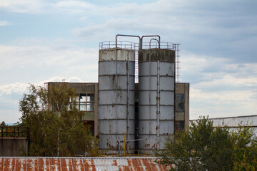Industrial silos tanks at factory facility against cloudy sky © Alexander