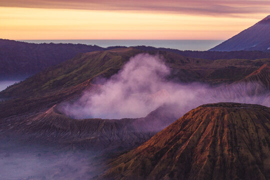 Volcanic peaks rise above a blanket of mist at sunrise near Mount Bromo in East Java, Indonesia.