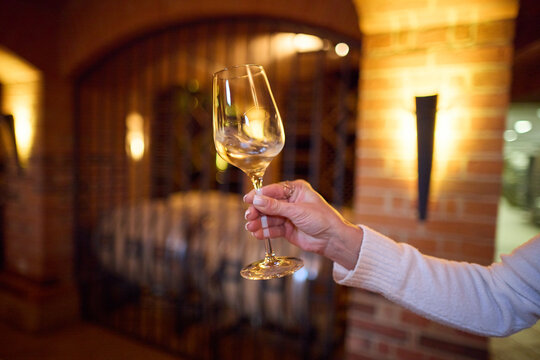 Close-up of a Hand Holding a Wine Glass in an Antique Brick Cellar