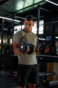 Man performing bicep curls with dumbbells in gym