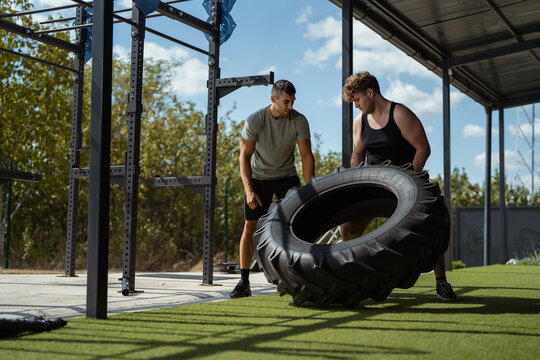 Personal trainer helping man with tire flip exercise