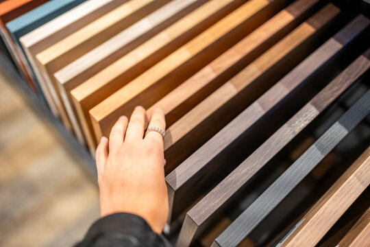 Woman touches countertop samples while choosing material in furniture showroom. Home renovation and interior design choice captured with selective focus and shallow depth of field