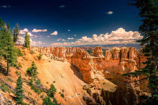 View of Bryce Canyon National Park featuring orange hoodoos, pine trees, and a deep blue sky, Utah, United States.