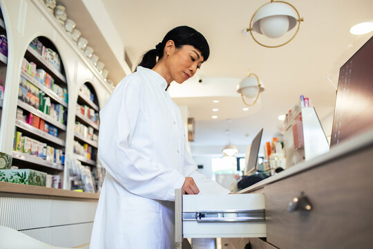 Pharmacist opening drawer at pharmacy counter