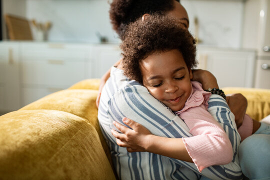 Smiling child hugging parent on sofa at home