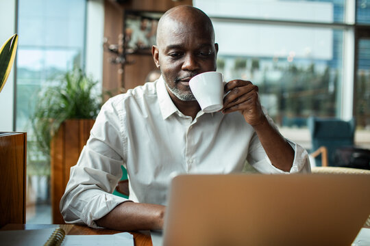Man sipping coffee while working on laptop in cafe