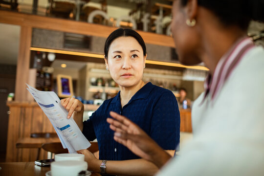 Woman pointing at report during cafe meeting