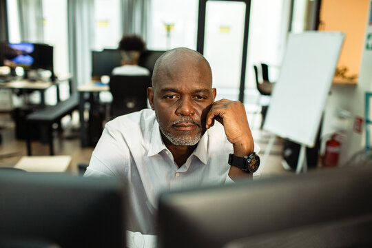 Tired office worker resting chin while staring at monitor in office