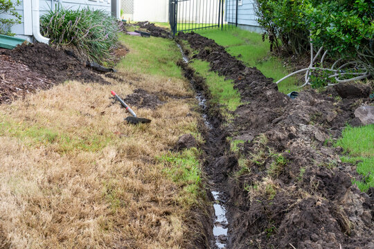 Ditch being dug in Yard to Install a downspout drain to prevent flooding