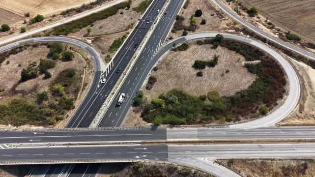 Aerial view of Trakiya Highway interchange with cars driving on asphalt roads through the dry landscape of Bulgaria.