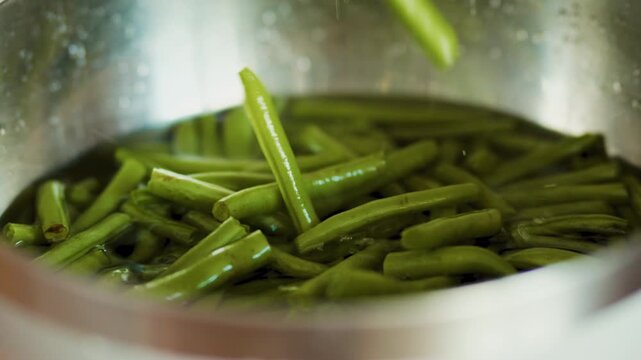Boiled green string beans inside a metal colander bowl
