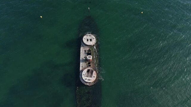 Top down aerial view flying backward over HMVS Cerberus historic shipwreck in ocean waters.