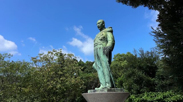 青空と木々に囲まれて立つ多賀山公園の東郷平八郎元帥像