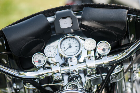 View of a motorcycle dashboard featuring chrome handlebars, analog gauges, and leather storage pouches in Canada.