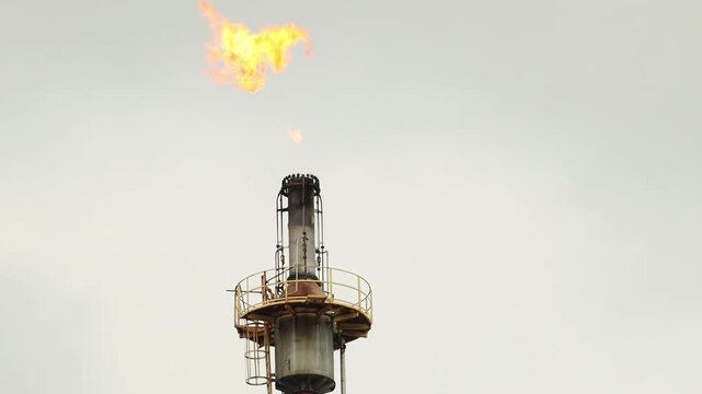 Fire broke out on the flare stack at oil and gas refinery plant. A blazing fire on the pipe of an industrial petroleum oil refinery factory.