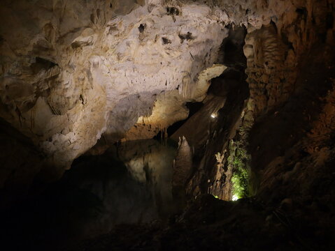 View of the interior of Vrelo Cave featuring intricate stalactites, stalagmites, and a calm underground lake in Matka, Komuna e Sopishtes, North Macedonia.