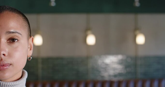 African American woman sitting left by green tiles, reacting offscreen, smiling, laughing