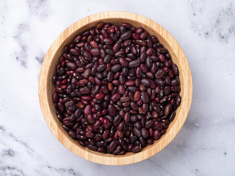 Red kidney beans in wooden bowl on marble table, top view