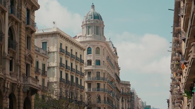 Ornate historical architecture with balcony pattern along Passeig de Lluis Companys during walks in Barcelona, Catalonia, Spain. Classic European city street with decorative facades and dome building