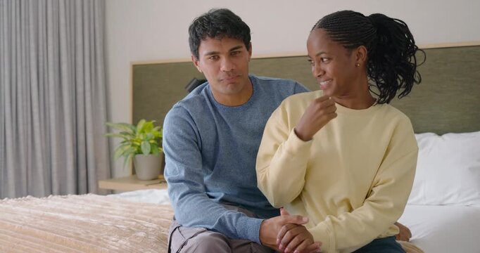 Diverse couple on bed, man noticing woman's shy touch and wrapping arm, showing affection