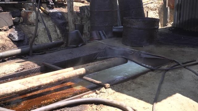 Traditional crude oil distillation process into diesel and kerosene using rustic manual equipment at Teksas Wonocolo petroleum field in Bojonegoro, East Java, Indonesia, showcasing local industry.