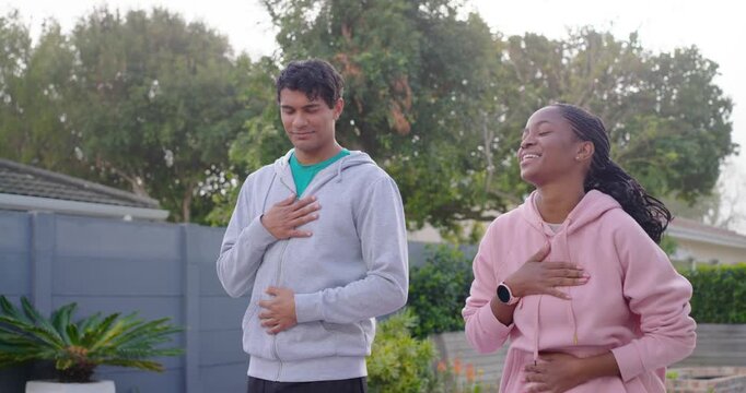 African American friends placing hands on chest and belly breathing to warm in garden tapping
