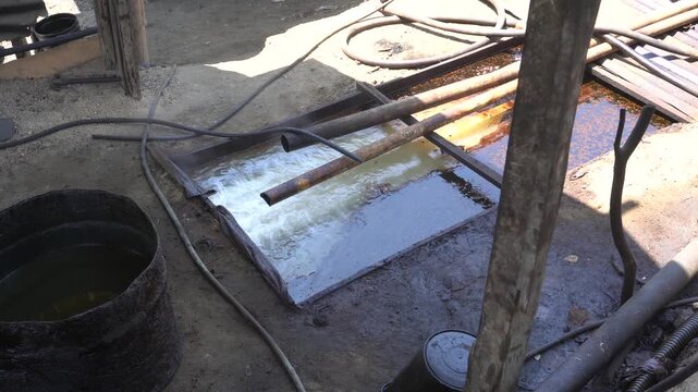 Traditional crude oil distillation process into diesel and kerosene using rustic manual equipment at Teksas Wonocolo petroleum field in Bojonegoro, East Java, Indonesia, showcasing local industry.