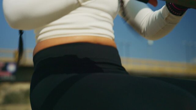 A determined woman performs a focused leg press exercise on outdoor fitness equipment. She is actively training to build strength and maintain a healthy, active lifestyle.
