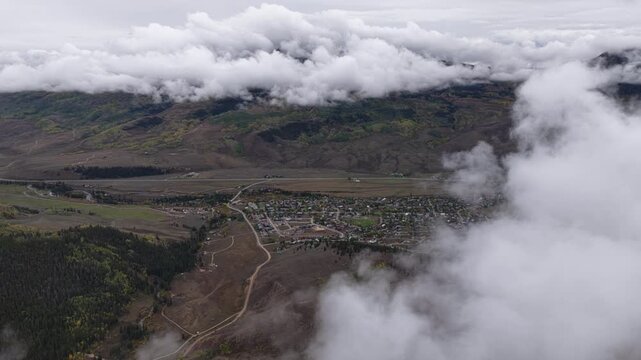 Aerial of small town and mountainous landscape with low clouds and fog overlooking Crested Butte South Colorado under the autumn season