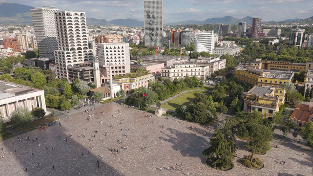 Aerial view of Skanderbeg Square featuring modern skyscrapers, historic buildings, the Et'hem Bey Mosque, and people walking across the plaza in Tirane, Qarku i Tiranes, Albania.