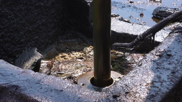 Traditional crude oil extraction from deep well at Teksas Wonocolo mining field in Bojonegoro, East Java, Indonesia. Raw black petroleum pulling process using traditional pipe rig in a rural area.