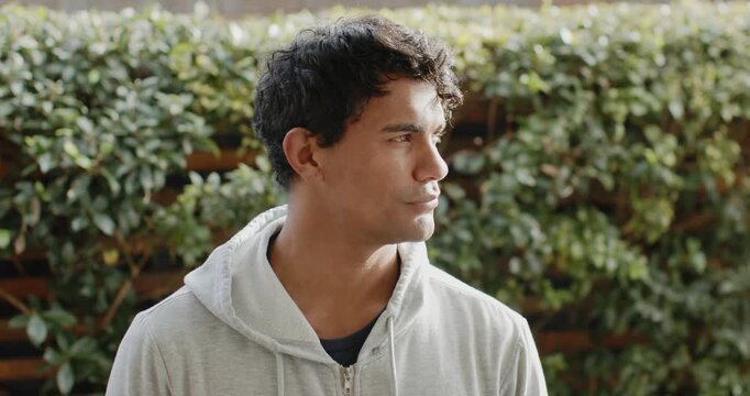 African American man camera-prompted, turning toward lens in yard, wearing gray hoodie, smiling