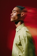 Fototapeta premium Side profile of a man with motion blur on a bold red background wearing a lime shirt in a minimalist expressive portrait