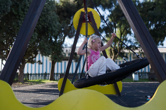 Carefree Little Girl Balancing and Playing on Web Nest Swing at Outdoor Playground