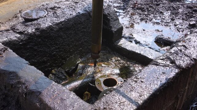 Traditional crude oil extraction from deep well at Teksas Wonocolo mining field in Bojonegoro, East Java, Indonesia. Raw black petroleum pulling process using traditional pipe rig in a rural area.