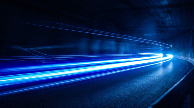 Blue light trails from a fast moving vehicle in a dark tunnel, illustrating speed and motion blur effect.
