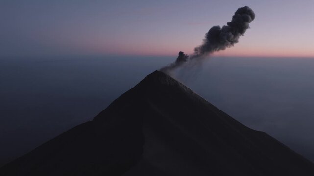 Aerial view of Acatenango volcano erupting with a plume of ash rising into the twilight sky over Alotenango, Sacatepequez Department, Guatemala.