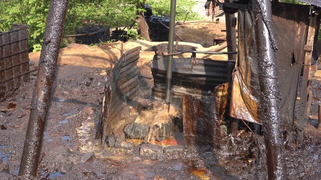 Traditional crude oil extraction using a pipe bailer at Teksas Wonocolo traditional oil field in Bojonegoro, East Java, Indonesia. Manual petroleum mining process from deep well with raw oil splash.