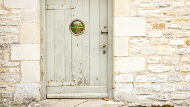 Old rustic wooden door with circular window set in stone wall exterior view