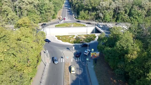 Aerial view of the Dragan Tzankov Boulevard roundabout with cars driving through the intersection surrounded by lush green trees in Sofia, Sofia City Province, Bulgaria.