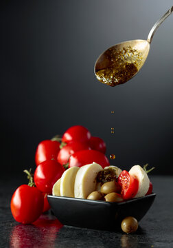 Mozzarella with pesto sauce, green olives, and red cherry tomatoes.