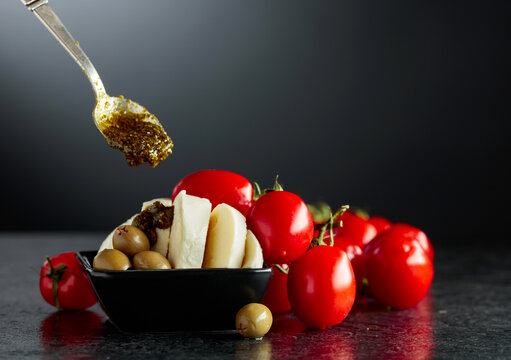 Mozzarella with pesto sauce, green olives, and red cherry tomatoes.