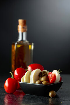 Mozzarella with pesto sauce, green olives, and red cherry tomatoes.