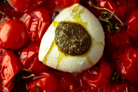 Mozzarella with pesto sauce and roasted red cherry tomatoes.