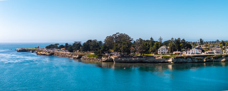 Aerial view shows the rugged coastline along West Cliff Drive with the Santa Cruz Surfing Museum lighthouse and coastal homes overlooking Monterey Bay in California.