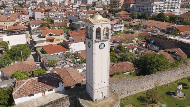 Aerial view of the Clock Tower of Elbasan surrounded by historic rooftops, stone walls, and lush greenery in Elbasan, Qarku i Elbasanit, Albania.