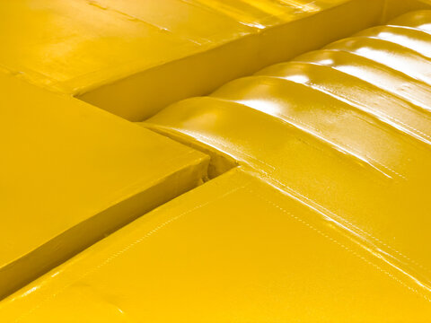 Close-up of a bright yellow painted plane wing with small highlights
